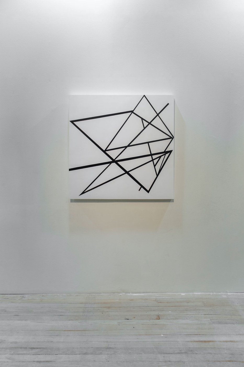 Esquina I, linhas pretas sobre quadrado branco, na parede da galeria