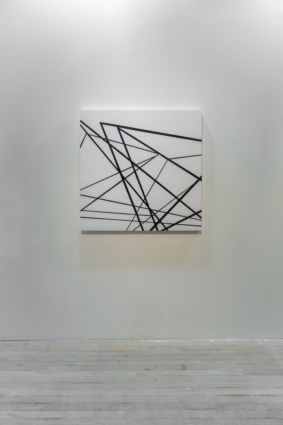 Esquina X, linhas pretas sobre quadrado branco, na parede da galeria
